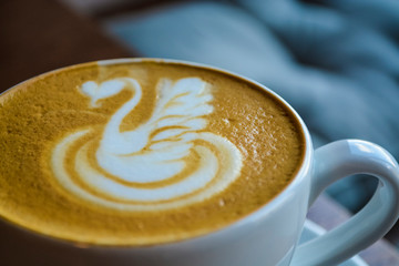 Fresh and fragrant coffee in coffee shop. A cappuccino cup with the drawing of a swan. Latte art. The invigorating drink.