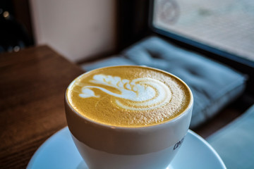 Fresh and fragrant coffee in coffee shop. A cappuccino cup with the drawing of a swan. Latte art. The invigorating drink.