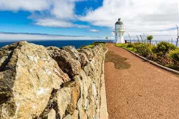 Stone Wall guiding to Lighthouse at Cape Reinga with Tasman Sea and Pacific, Northland, New Zealand