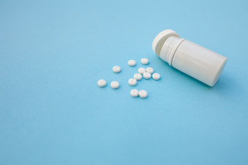 Pills and pill bottle on blue paper background