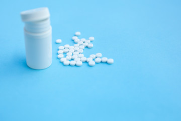 Pills and pill bottle on blue paper background