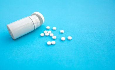 Pills and pill bottle on blue paper background