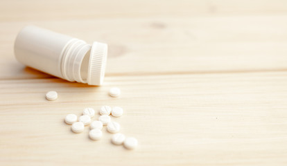 Fototapeta na wymiar Pills and pill bottle on white wooden background
