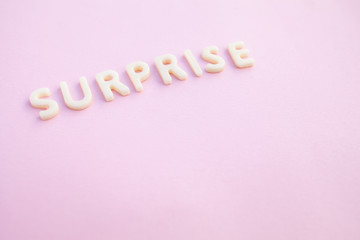 Surprise word written in voluminous white letters on a beautiful pink background.