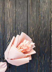 Beautiful bouquet of dry pink flowers on a wooden black background. Minimalism, space for text. Gift Card