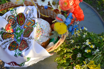 Stylish basket with painted eggs, bread with spring flowers and candle, top view. Easter food for blessing in church. 