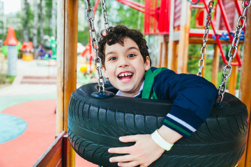Obraz premium Little pretty boy is having fun outdoor. Playing in children zone in amusement park.