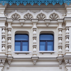 Close up view on a facade of white ancient building with decorative ornaments and two windows
