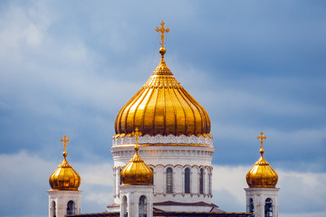 Fototapeta na wymiar Close up view on a gilded domes of Cathedral of Christ the Savior in Moscow (Russia) on a background of dramatic cloudy sky