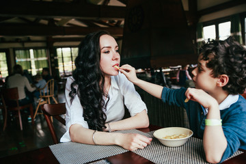 Mother and son eating fries in restaurant. Funny family dinner