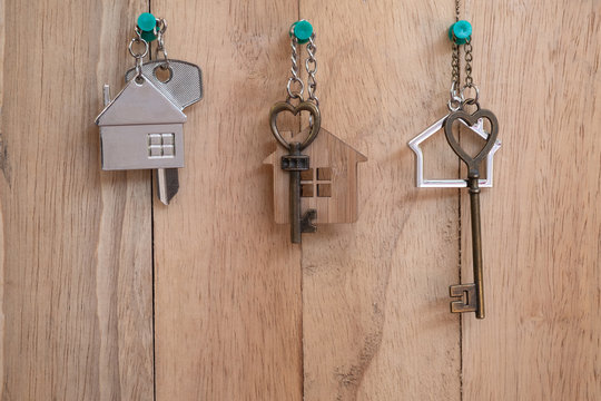 Heart shape house key with home keyring on wood fence background