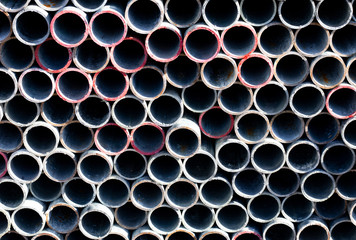 End view on scaffold poles stockpile stacked on storage rack on building construction site 