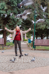 Pigeons and woman are at the park.