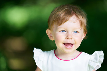 Portrait of a smiling one-year-old girl with blue eyes