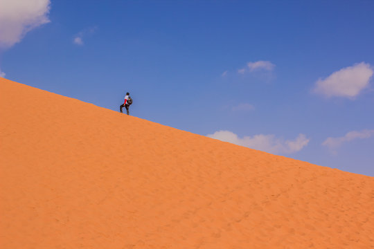 travel tourism wallpaper pattern concept photography with tourist man on a yellow dune somewhere in Wadi Run desert nature landscape environment in Jordan Middle East country on blue sky background