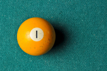 Old billiard ball number 1 yellow color on green billiard table, copy space
