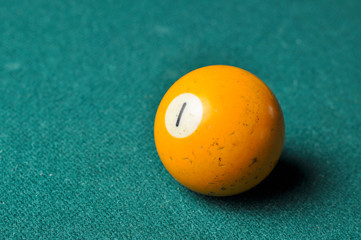 Old billiard ball number 1 yellow color on green billiard table, copy space