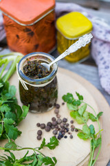 Green adjika. Traditional Georgian spice blend, mix of spices with fresh green coriander, hot chilly pepper in glass jar on wooden board. Food from Georgia.