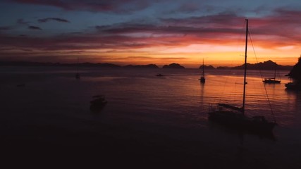 Aerial view of boats and yachts in the tropical bay on the sunset. El Nido, Palawan, Philippines. Marine tropical sunset over the sea. Travel concept.