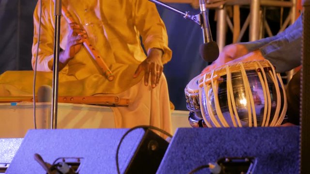 Two men playing traditional Indian tabla drums and flute on stage of ethnic open air concert. Relaxation, meditative and traditional ethnic music concept