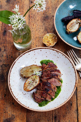 Lamb leg fillet with wild garlic puree, roast garlic bulb and jerusalem artichoke
