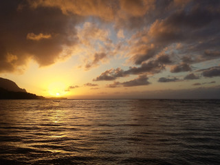 Fototapeta na wymiar Glowing sunset with dramatic clouds on the waters of Kauai, Hawaii