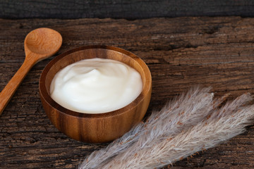 Natural homemade plain organic yogurt in wooden bowl and wood spoon on wood texture background