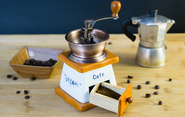 Old Italian coffee grinder close-up and already grated fresh coffee, in the background a moka and...
