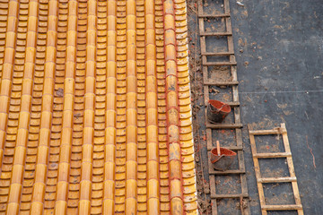 repairing the yellow roof tile with stepladder and bucket