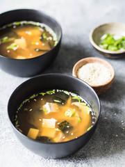 Japanese miso soup with oyster mushrooms in a black bowls on a grey background