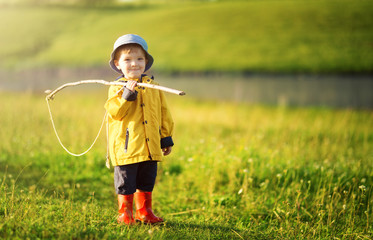 Cute little boy in hat holding big fishing net at the ready.