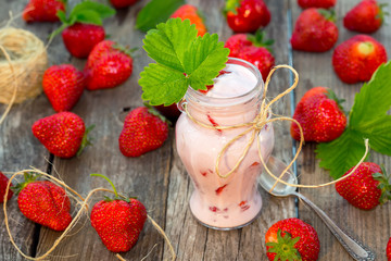 Organic yougurt in jar with fresh strawberry on rustic wooden table
