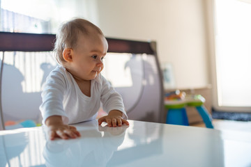 Caucasian baby girl based on a table in bright room