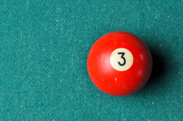 Old billiard ball number 3 red color on green billiard table, copy space