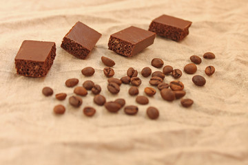 Milk porous chocolate sweets with coffee beans on a linen texture background.