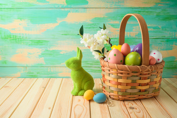 Easter holiday background with easter eggs in basket and bunny on wooden table