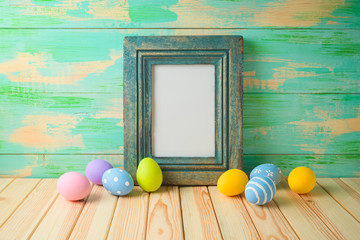 Photo frame or artwork display mock up on wooden table with easter eggs.