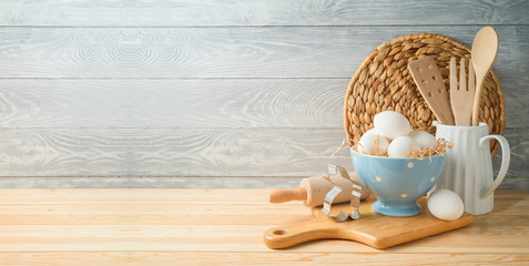 Easter baking background with eggs and kitchen utensils on wooden table