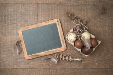 Easter holiday background with brown easter eggs decorations and chalkboard on wooden table.