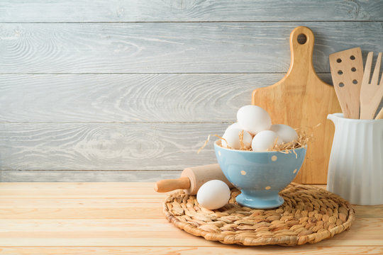 Easter baking background with eggs and kitchen utensils on wooden table