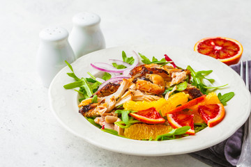 Grilled chicken and orange salad with onion in white plate on a white background.