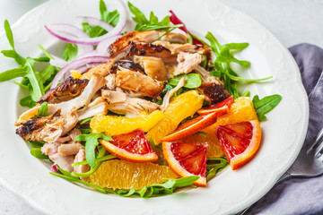 Grilled chicken and orange salad with onion in white plate on a white background.