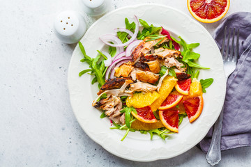 Grilled chicken and orange salad with onion in white plate on a white background.