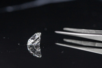 Diamond with tweezers on reflection background