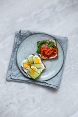 Smorrebrod - danish open sandwich with fish, vegetables, cheese on marble background. Top view with copy space