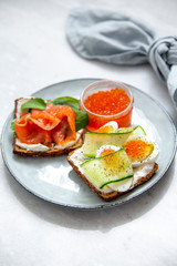 Smorrebrod - danish open sandwich with red caviar, fish, vegetables, cheese on marble background. Top view with copy space