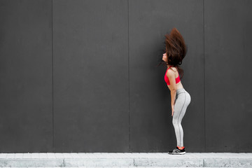 Sport fitness girl in fashion sportswear dancing in the street, on gray wall background ,outdoor sports. Urban style.