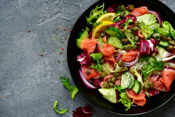 Vegetable salad with salted salmon in a black bowl.Top view with copy space.