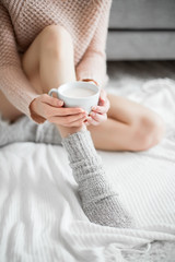Woman in a cozy room with a cup of cocoa in her hand.