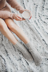 Woman in a cozy room with a cup of cocoa in her hand.